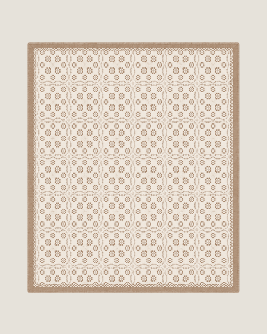 Terra Versatile Quilt in Sandstone, a neutral organic cotton quilt used as the base layer on a bed