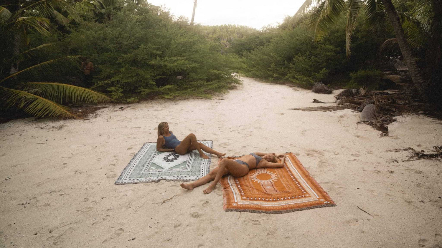 girls on throw rugs at the beach